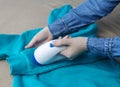 Machine for removing pellets. The girl uses a special device to remove lint from clothes. Restoration of old damaged clothes Royalty Free Stock Photo