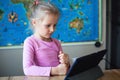 Girl uses a tablet for a game and smiles, laughs. Child using gadgets to study. Education and distance learning for kids. Royalty Free Stock Photo