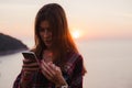 Girl using cellphone near the sea in sunrise or sunset. Royalty Free Stock Photo