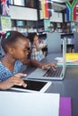 Girl using digital tablet and laptop in library