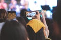 A girl using her smartphone for take a picture in music concert