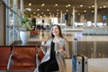 Girl using internet by tablet in airport hall near valise and showing thumbs up. Royalty Free Stock Photo