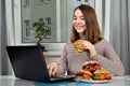 Girl using a laptop and eating a vegetarian sandwich Royalty Free Stock Photo