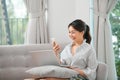 Girl using laptop and smartphone. Young woman in casual clothes with her legs crossed sitting on sofa at cozy home interior. Royalty Free Stock Photo