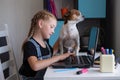 girl using laptop studying at home. Dog sit on table. Royalty Free Stock Photo