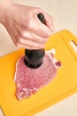 Girl using meat tenderizer to prepare the pork Royalty Free Stock Photo