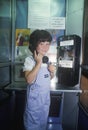 A girl using a pay telephone Royalty Free Stock Photo