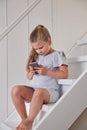 Girl using phone on stairs at home