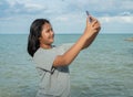 A girl using a phone to take a selfie on a sea background Royalty Free Stock Photo