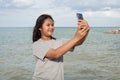 A girl using a phone to take a selfie on a sea background Royalty Free Stock Photo