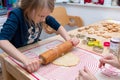 A girl is using the rolling pin to roll out the dough on the tab Royalty Free Stock Photo