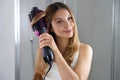 Girl using round brush hair dryer to style hair at the mirror in an easy way at home Royalty Free Stock Photo