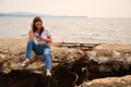 Girl using smartphone sitting on an old concrete pier Royalty Free Stock Photo