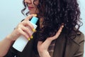 Girl using spray to make curly hairstyle. Woman with long curly hair. Cosmetics for hair care Royalty Free Stock Photo