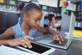 Girl using tablet computer and laptop in library