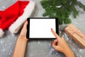 Girl using tablet technology in home, person holding computer on background Christmas decoration, female hands texting, mockup tem