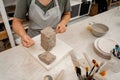 Girl is using a wire cutter to cut off a piece of clay before modeling the product. Slicing off a chunk of clay from a