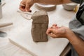Girl is using a wire cutter to cut off a piece of clay before modeling the product. Slicing off a chunk of clay from a