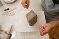 Girl is using a wire cutter to cut off a piece of clay before modeling the product. Slicing off a chunk of clay from a