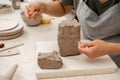 Girl is using a wire cutter to cut off a piece of clay before modeling the product. Slicing off a chunk of clay from a