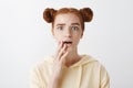 Girl is very nervous hearing shocking revelation. Attractive young woman with red hair and two buns hairstyle holding