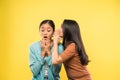 a girl is very shocked when her friend talks whispering in her ear