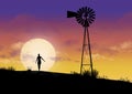 A girl and a vintage windmill are seen in front of a sunset sky Royalty Free Stock Photo