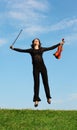 Girl with violin jumps on grass against sky Royalty Free Stock Photo