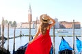 Girl visiting Venice in Italy. Back view of beautiful young woman in red dress enjoying view of Venetian Lagoon Royalty Free Stock Photo
