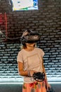 A girl in a VR helmet plays games in the computer room and controls joysticks Royalty Free Stock Photo