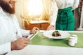 Girl waiter serves his dish in restaurant to a man Royalty Free Stock Photo