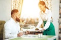 Girl waiter serves his dish in restaurant to a man Royalty Free Stock Photo