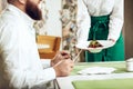 Girl waiter serves his dish in restaurant to a man Royalty Free Stock Photo