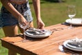 Girl the waiter in a summer cafe under the open sky sets the dishes on a wooden table