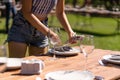 Girl the waiter in a summer cafe under the open sky sets the dishes on a wooden table