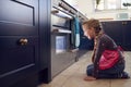 Girl Waiting By Oven In Kitchen At Home For Cakes To Bake