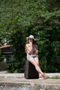 Girl waiting with rolling upright suitcase at docks