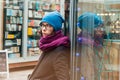 Girl waits leaning to a window of a shop at the shopping street