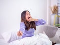 The girl wake up in the morning lying on the bed, still looking sleepy, twisting and yawning in the bedroom. lazy woman in weekend Royalty Free Stock Photo