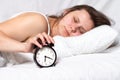 Girl wakes up in the morning. Young woman lying in bed in the morning. She is waking up with an alarm clock Royalty Free Stock Photo