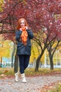 Girl walk on pathway in city park with red trees, fall season Royalty Free Stock Photo