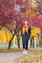 Girl walk on pathway in city park with red trees, fall season Royalty Free Stock Photo