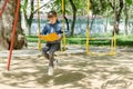 Girl on a walk reading a book swinging on a swing at the playground