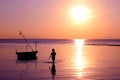 The girl walked on the beach with a fishing boat and sunset.