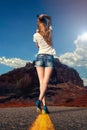 Girl walking along the road in the desert