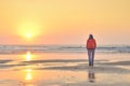 Girl walking on beach at sunset.