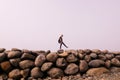 A girl walking on the coastal mound of large stones against the clear sky with a copy space