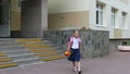 Girl walking down stairs with backpack and flowers bouquet from school door. Back to school concept. summer day hanheld Royalty Free Stock Photo