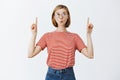 Girl walking down street seeing it is going rain. Cute tender european female student in glasses and pink striped t