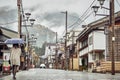 Girl Walking down Street of Traditional Japanese Mountain Town in fog and rain